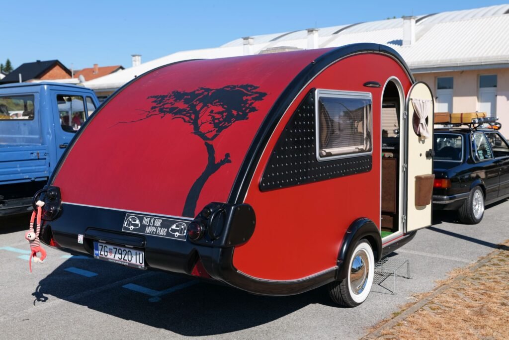 A modern lightweight teardrop travel trailer hitched to a silver SUV at a mountain campsite during sunset. practical detail