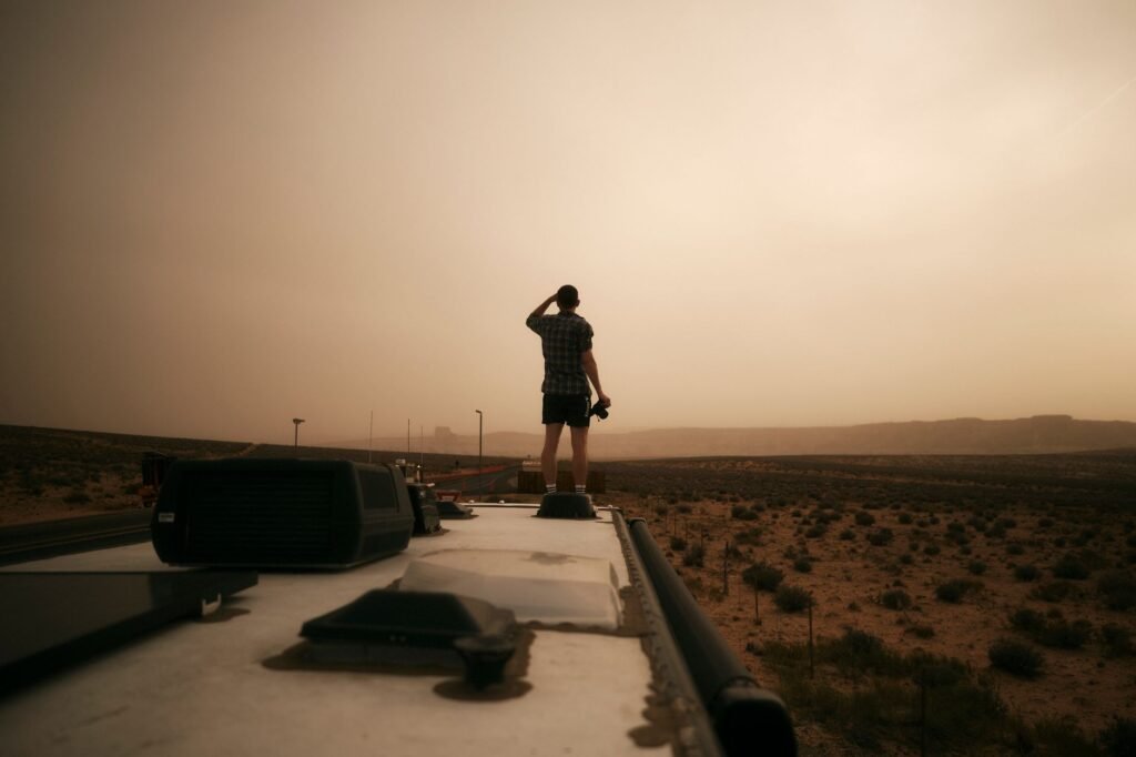 A travel trailer parked on the side of a road as a massive dust storm haboob approaches in the Arizona desert. practical detail