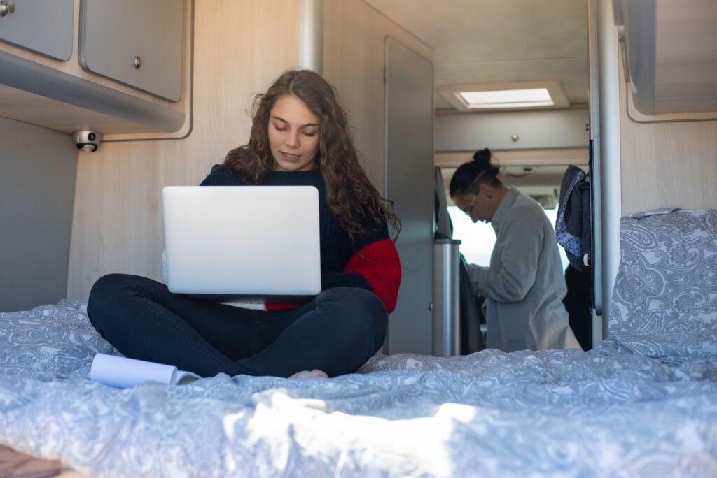 A modern travel trailer kitchen featuring a 2026 induction cooktop and a digital battery monitoring system as part of a propane-to-electric conversion. practical detail